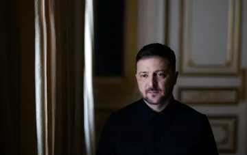 Президент Украины Владимир Зеленский в темной рубашке, смотрящий в камеру на фоне роскошного интерьера — иллюстрация к статье о западных задержках в развитии украинской баллистики