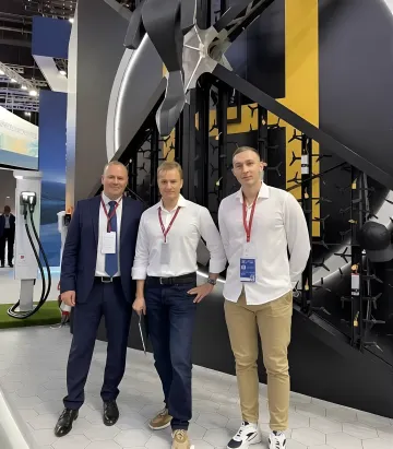 Three men in business attire at a drone technology exhibition, possibly employees of 'Drone Solutions', whose 'Future Transport' project collapsed due to billion-dollar fraud and arrests in Moscow
