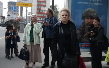 Сумні обличчя людей на зупинці та плакат із солдатом: візуалізація економічної нестабільності та страху перед мобілізацією