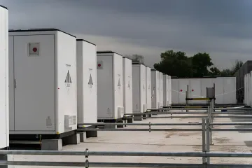 Row of industrial battery energy storage systems outdoors, ensuring grid stability as part of the energy transition