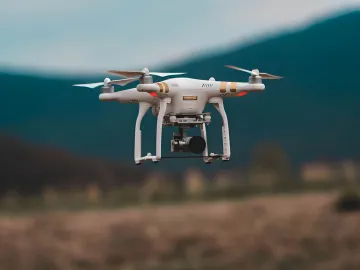 Weißer DJI-Drohne im Flug vor Bergkulisse — Illustration zur Nachricht über die rückwirkende Widerrufung von FCC-Genehmigungen für Drohnen der „militärischen Klasse“, die DJI und andere Marken betreffen