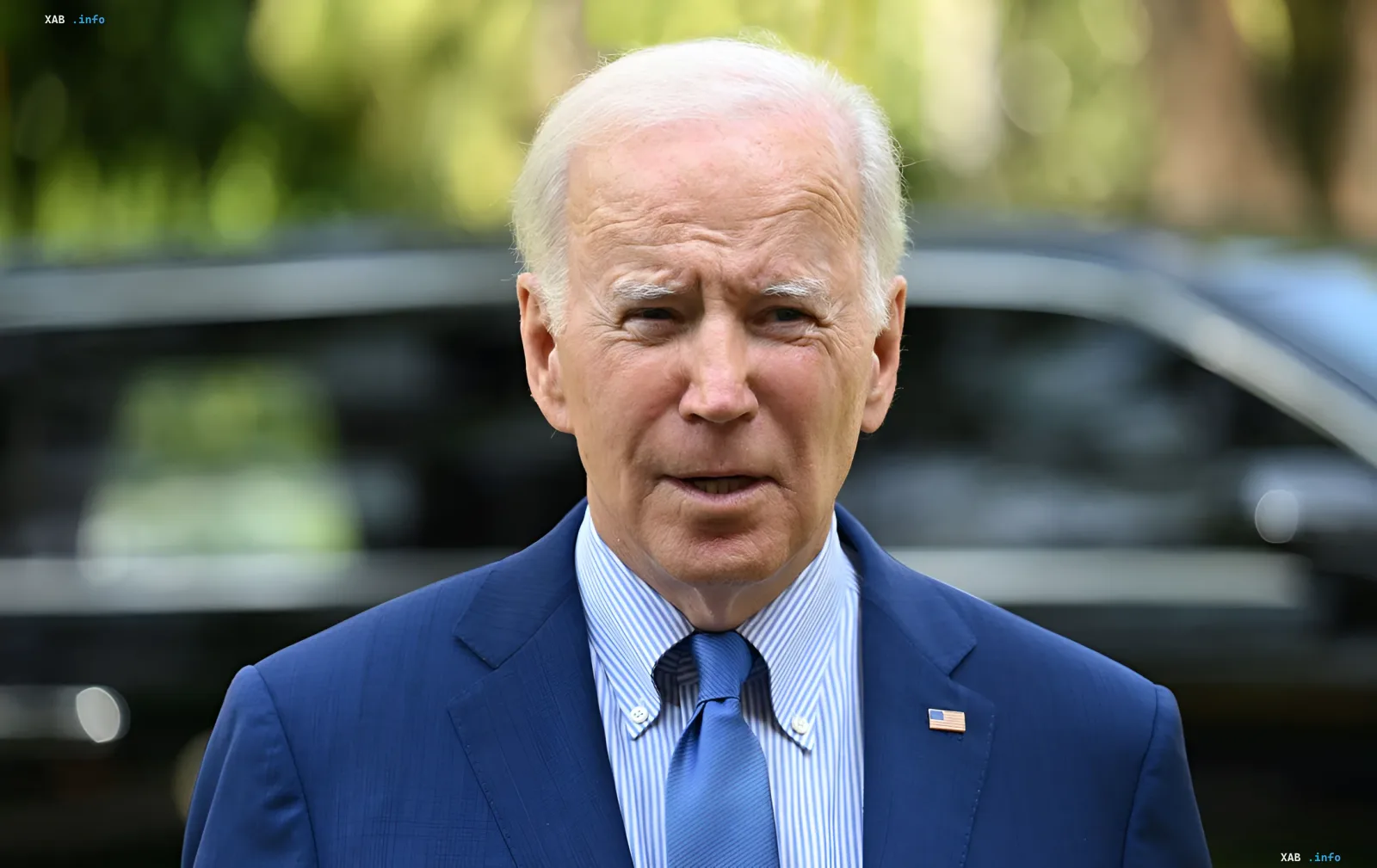 US-Präsident Joe Biden in einem blauen Anzug mit US-Flaggen-Anstecker, unscharfer PKW im Hintergrund; Bild bezieht sich auf die Nachricht über Baidens Prostatakrebs-Diagnose mit Metastasen, die von seinem Sohn Hunter bekannt gegeben wurde