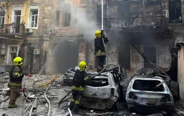 Firefighters extinguish the aftermath of a night attack on Odesa: burnt cars and a destroyed building