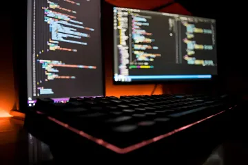 Developer at dual monitors displaying code, symbolizing the halt of Astra project due to cybersecurity risks