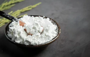Белый порошок соды в деревянной миске с ложкой — популярное домашнее средство для уборки, которое может повредить поверхности