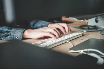 Hände eines Programmierers auf der Tastatur: Illustration zur Nachricht, dass KI die Arbeitsbelastung erhöhen sollte, nicht mehr freie Tage gewähren