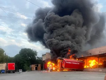 Пожар на складе Новой почты: горящий красный грузовик и терминал, охваченные огнем и дымом