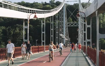 People walking and cycling on a bridge on a sunny day, despite the forecast of extreme heat and storms in Ukraine on August 9