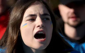 Украинская девушка с флагом на лице кричит в поддержку армии, отражая общественные настроения 2026 года