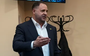 Former Head of the Office of the President of Ukraine Andriy Yermak in a suit with a Ukrainian flag on the lapel, holding a pen and speaking, symbolizing the change in his preventive measure.