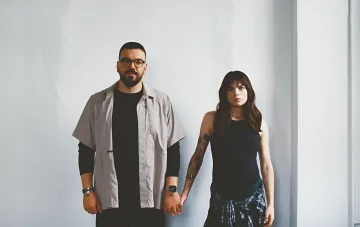 Photographers Liberov holding hands against a white wall, symbolizing their unity and support in their work at the front line