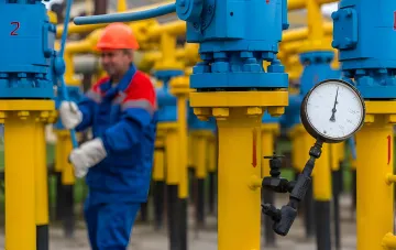 Рабочий в защитной экипировке управляет газовым клапаном на фоне желтых трубопроводов, символизируя важность экспорта для украинской газовой отрасли.
