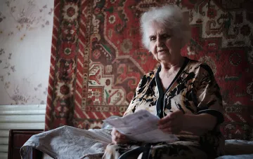 Пожилая женщина внимательно изучает документы, связанные с перерасчетом пенсии в 2026 году