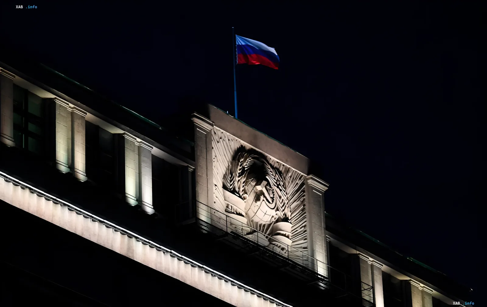 Night view of a building with the Russian flag and USSR emblem, symbolizing the political atmosphere surrounding the removal of the 'Yabloko' party from the State Duma elections