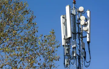 Mobilfunkmast vor blauem Himmel, der die Risiken einer Kommunikationsunterbrechung aufgrund von Lücken im Grundbuchgesetz symbolisiert, wie von der Firma 'Telas' gewarnt.
