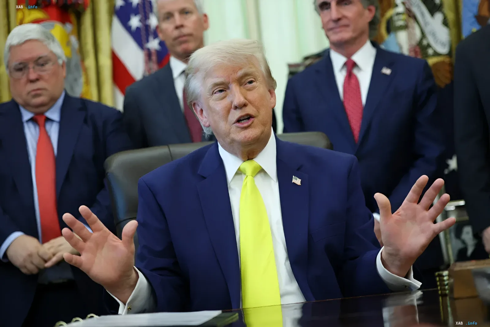Дональд Трамп в синем костюме и ярко-желтом галстуке жестикулирует во время выступления, требуя компенсаций от Ирана за 50 лет