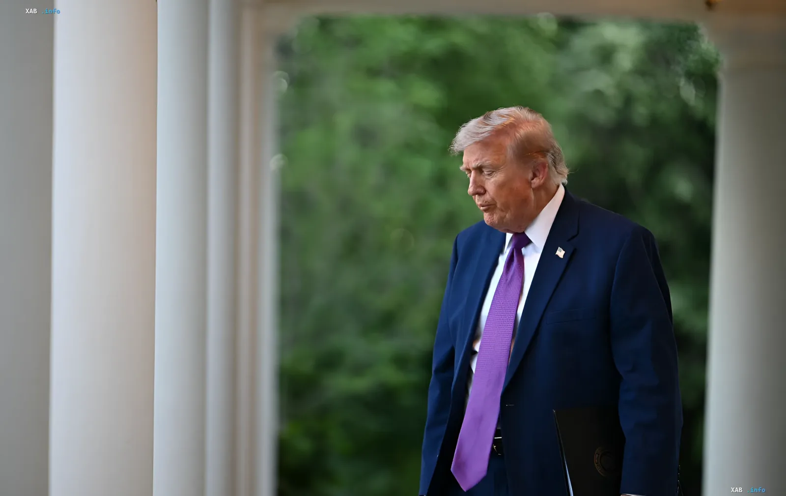Дональд Трамп у синьому костюмі з фіолетовим краваткою, тримаючи папку, на тлі колон та зелені — символ рішучості у питанні відповідальності Ірану за 50 років конфліктів