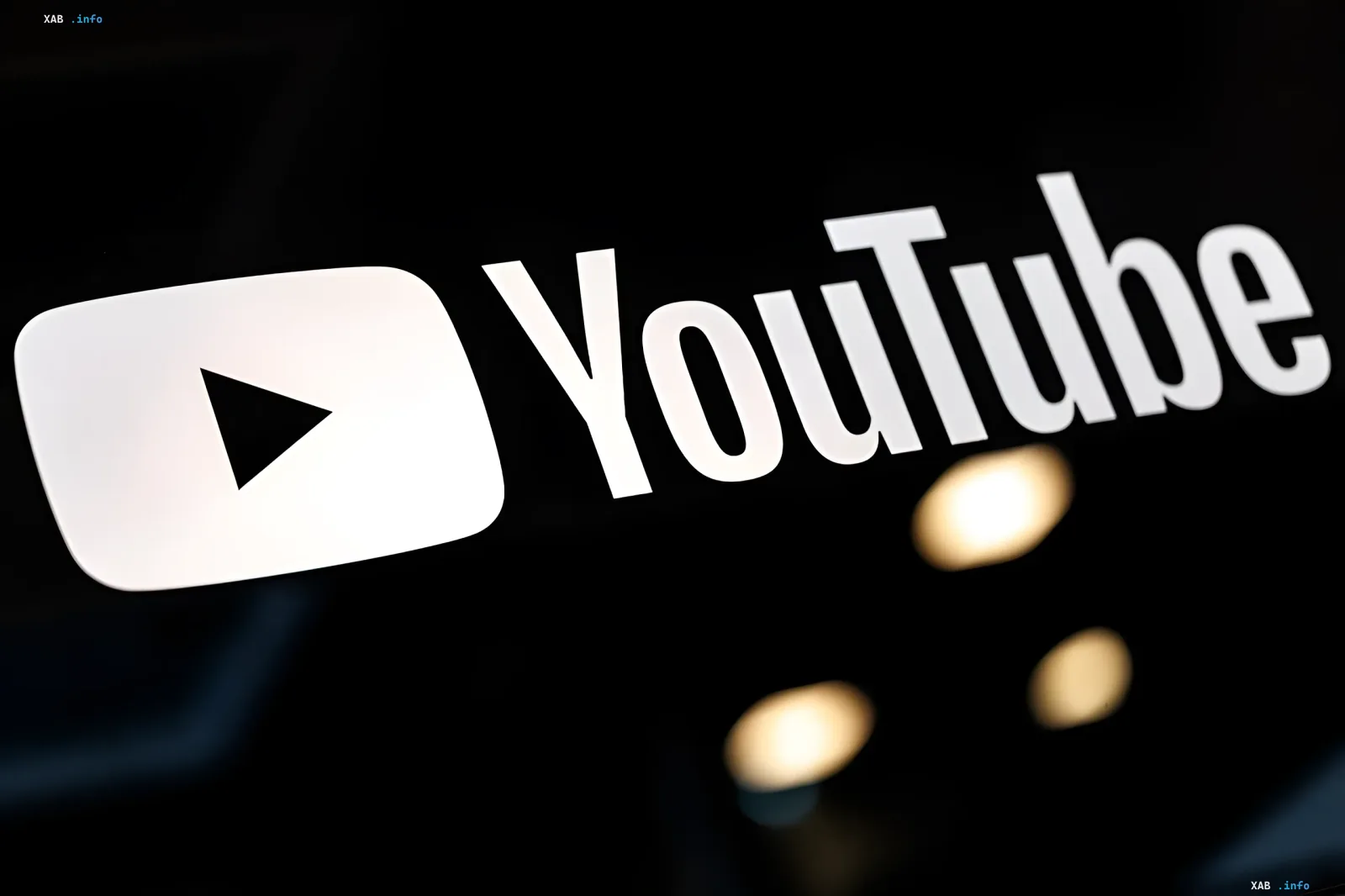 YouTube logo on a black background with blurred lights, symbolizing new monetization rules and the fight against AI-generated content in 2026