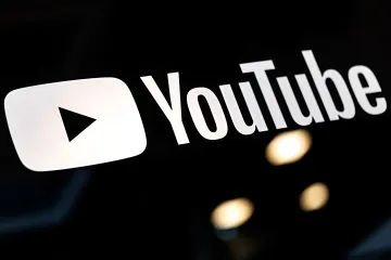 YouTube logo on a black background with blurred lights, symbolizing new monetization rules and the fight against AI-generated content in 2026