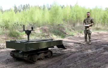 Военный оператор управляет гусеничным роботом с РЭБ-оборудованием в лесу — пример защиты тяжелой техники от асимметричных угроз