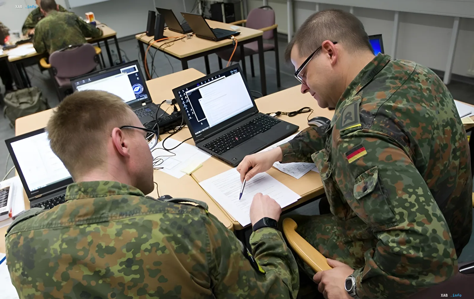 Німецькі військовослужбовці в камуфляжній формі працюють за ноутбуками в навчальному класі, аналізуючи дані для превентивної боротьби загрозами.