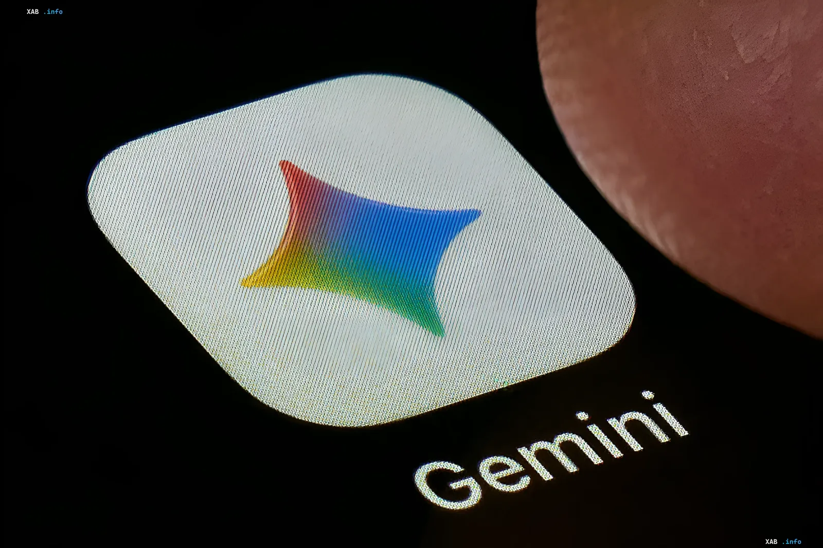 Логотип Gemini на экране смартфона с пальцем рядом, символизирующий миллиардную аудиторию и лидерство Google в сфере ИИ