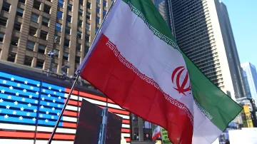 Iranian flag in front of an American flag in a city, symbolizing Iran's ultimatum to the US regarding the Strait of Hormuz