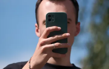 Person taking a selfie with a green-cased smartphone, symbolizing reliance on mobile connectivity — relevant amid Ukraine’s Ministry of Digital Transformation tightening network autonomy requirements
