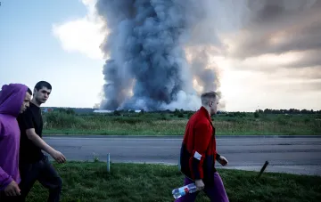 Huge column of black smoke over Wildberries warehouse near Voronezh, people walk past the road against the backdrop of the fire