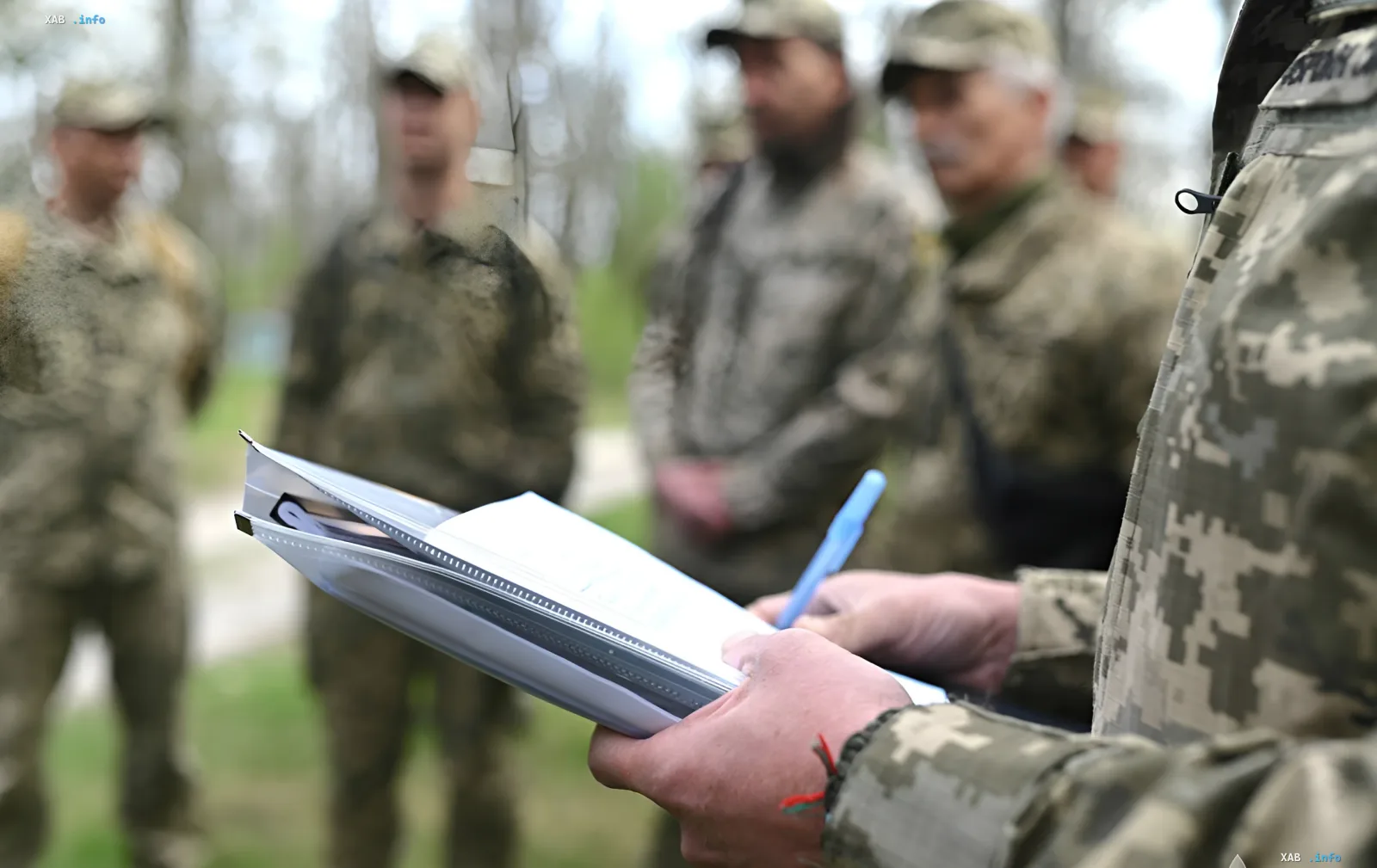 Співробітник ТЦК заповнює документи в Миколаєві, на фоні група військових