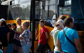 People waiting to board an evacuation bus amid a psychological support program