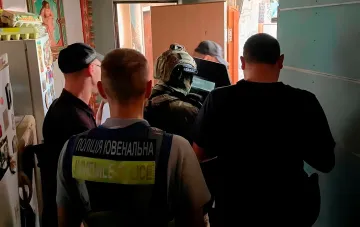 Ukrainian juvenile police officers in vests with 'JUVENILE POLICE' written on them detain teenagers in a residential apartment in Kyiv