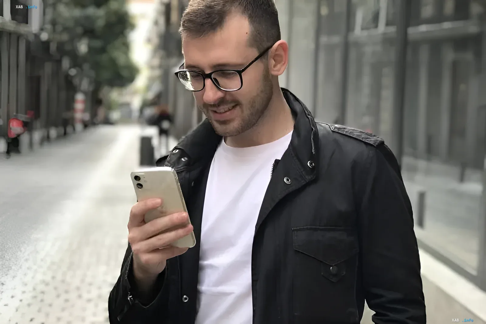 Молодой мужчина в очках смотрит на смартфон на улице, иллюстрируя использование персонализированной ленты VK на основе единого нейропрофиля