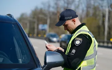 Ukrainischer Polizist überprüft die Dokumente des Fahrers, der im Auto auf der Straße im Jahr 2026 bleibt