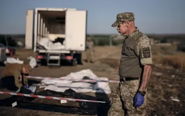 Співробітник кримінальної поліції України оглядає місце ексгумації тіл загиблих у полоні, підтверджуючи дані про 375 жертв