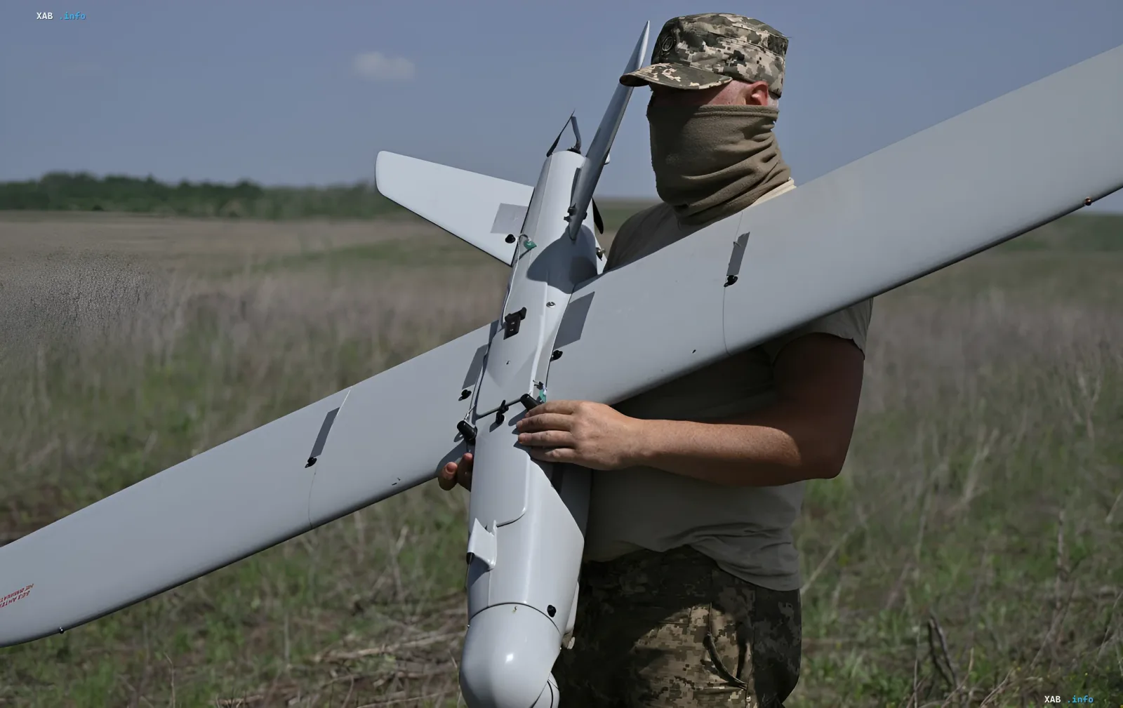 Военнослужащий держит разведывательный дрон на фоне поля, иллюстрируя тему отмены «Дронницы-2026» в Великом Новгороде из-за угрозы украинских ударов