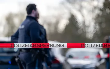 Polizist steht hinter der Absperrbande „POLIZEIABSPERRUNG“ vor dem Hintergrund von Rauch einer Phosphorgranate aus dem Zweiten Weltkrieg, die in Hessen aufgrund von Dürre gefunden wurde