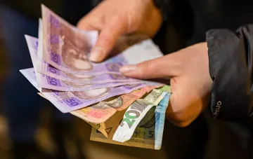 Руки считают украинские гривны — иллюстрация к новости об ускорении инфляции в Украине в июле 2026 года до 7,7%