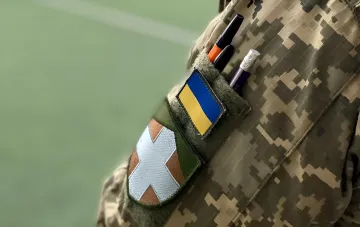 Украинский военный с флагом Украины на форме, символизирующий защиту и жертвенность ветеранов