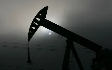 Силуэт нефтяной вышки на фоне заката, символизирующий рост цен на нефть из-за конфликта в Персидском заливе