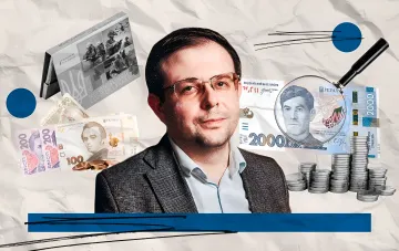 Новая банкнота 2000 гривен с портретом Василя Стуса, увеличенная лупой, на фоне других украинских денег и монет, символизирующих коллекционный рынок.