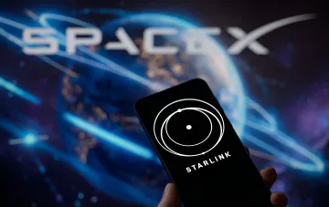 Смартфон с логотипом Starlink на экране на фоне логотипа SpaceX и Земли, иллюстрирующий тему роуминга и оплаты услуг спутникового интернета в Польше и Украине