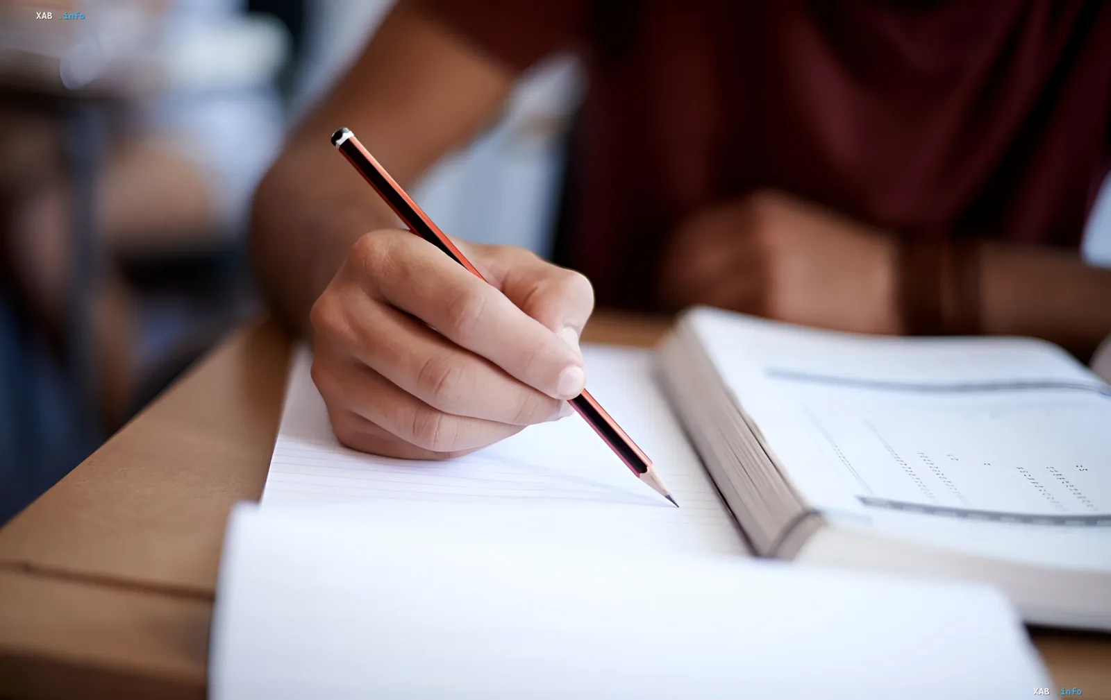 Schüler schreibt mit einem Stift in ein Heft während einer Prüfung, was die NMT-2027-Reform und den Umzug der Tests in Schutzräume illustriert.
