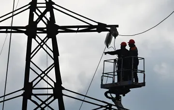 Электромонтеры в красных касках работают на высоте, устраняя повреждение на высоковольтной линии электропередач
