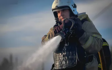 Пожежник гасить пожегу після удару по Києву в Деснянському районі 12 серпня