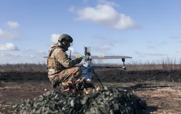 Ukrainian soldier prepares a drone with Ukrainian insignia for launch in an open field — symbol of Ukrainian countermeasures against Russian 'Geran' drones in Crimea