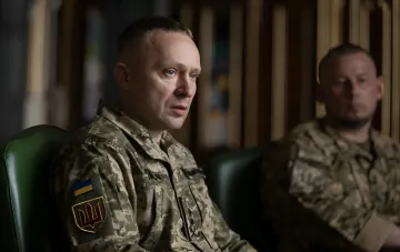 Ukrainischer Offizier in Tarnuniform mit ukrainischer Flagge und AFU-Emblem diskutiert Durchbruch an der Alexandrowka-Richtung