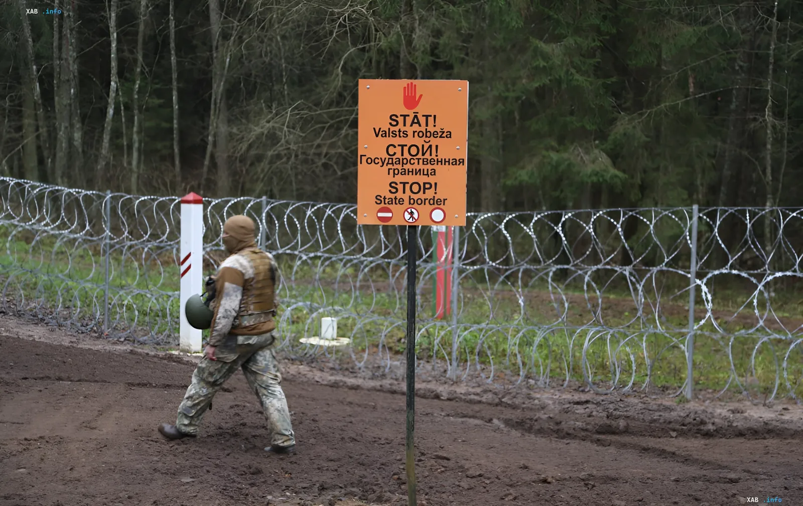 Soldat patrouilliert verstärkte litauische Grenze mit Stacheldraht und Warnschild