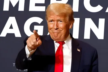 Дональд Трамп вказує пальцем на фоні гасла 'America Again', символізуючи політичні зміни та чистки в адміністрації США