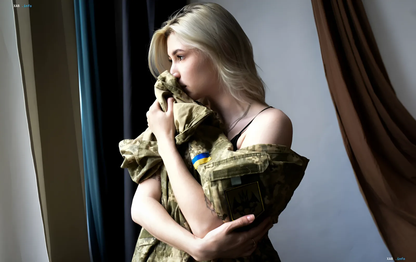 Женщина обнимает военную форму с украинским флагом, символизируя скорбь семьи погибшего военного в контексте налоговых разъяснений ГНС